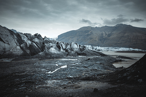 Dramatic landscape showing melting glacier with volcanic ash