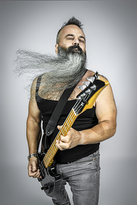 rocker with guitar and long beard plays with his eyes closed. 