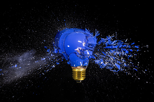 traditional blue bulb breaks and explodes on a black background.