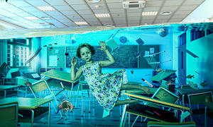 little girl floating under water in a flooded classroom.