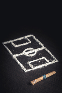 rolled up banknote and football field drawn with cocaine drugs b