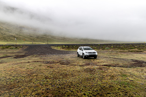 White suv parked on side of empty road leading into foggy mounta