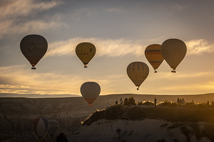 Hot air balloons fly at dawn over the hills of Goreme.