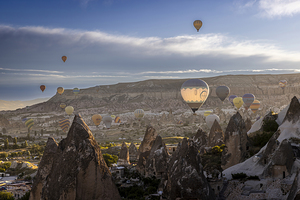 hot air balloons fly  over the city of goreme at sunrise