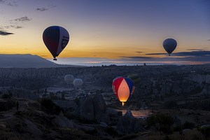 Hot air balloons fly at dawn over the hills of Goreme.