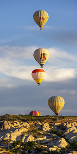 group of hot air balloons fly near Goreme at sunrise.