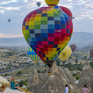tourists take pictures with hot air balloons in the background