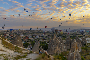 tourists watch the spectacle of the hot air balloons flying abov