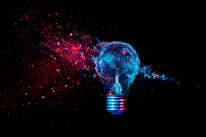 glass explosion of a filament light bulb on black. 