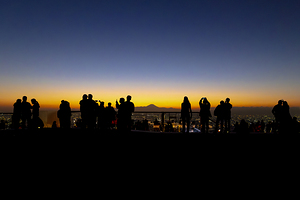 Silhouetted figures observing sunset cityscape