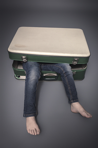 legs protruding from an old suitcase 