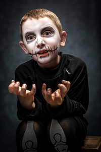 child dressed as skeleton in scary pose.