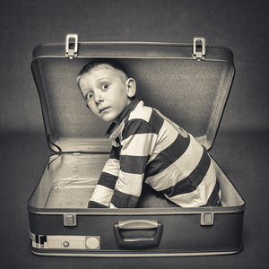 child with astonished expression in a suitcase