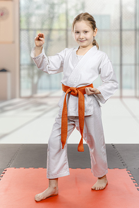 Young karate girl with orange belt posing
