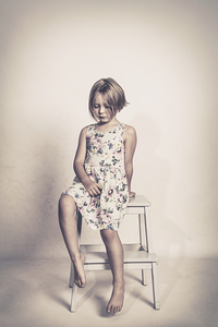 sad little girl sits on a stool 