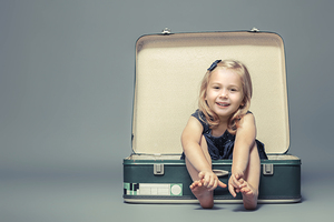 blond girl sitting in a vintage suitcase. 