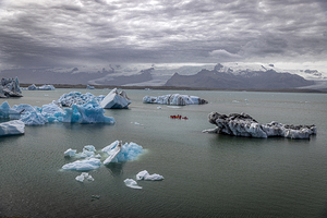 Group of athletes kayaking around melting icebergs in iceland