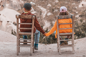 children sitting on wooden chairs holding hands
