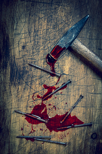 hammer and bloody nails on a wooden