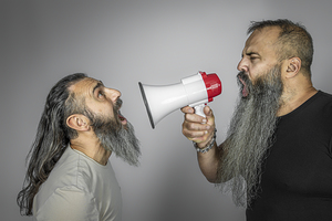 man yells with megaphone to another man