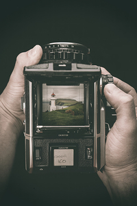 hands hold a medium format film camera dark background