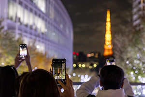 Tourists take a smartphone photo of the Tokyo tower 