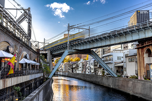 Train crossing bridge over canal in urban japan at sunset