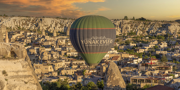 hot air balloon flies low over the city of goreme
