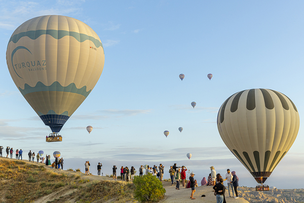 people watch the spectacle of hot air balloons flying over gorem