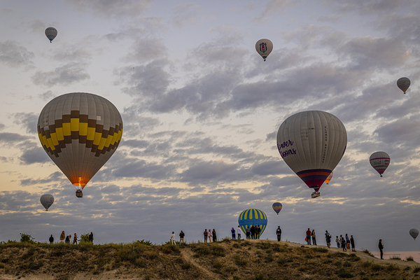 tourists watch the hot air balloon show above goreme at dawn
