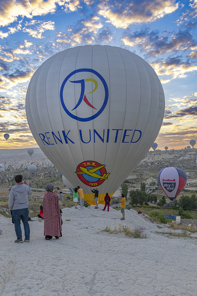 hot air balloon flies near the tourists over the hills of goreme Print