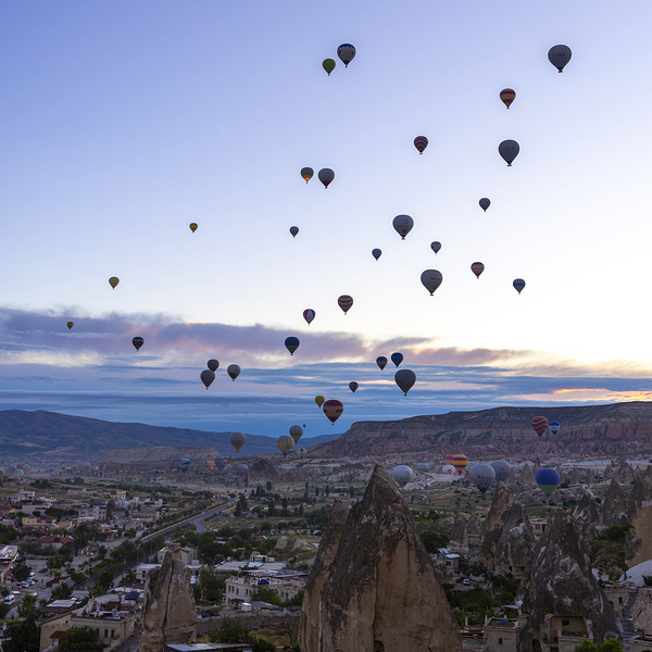 several hot air balloons fly at dawn in the sky of goreme