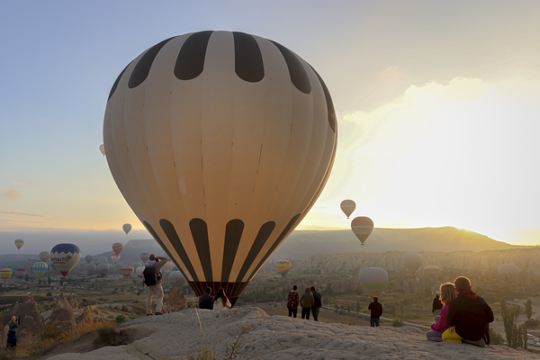 tourists watch the flight of hot air balloons