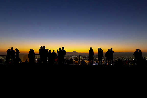 Silhouetted figures observing sunset cityscape