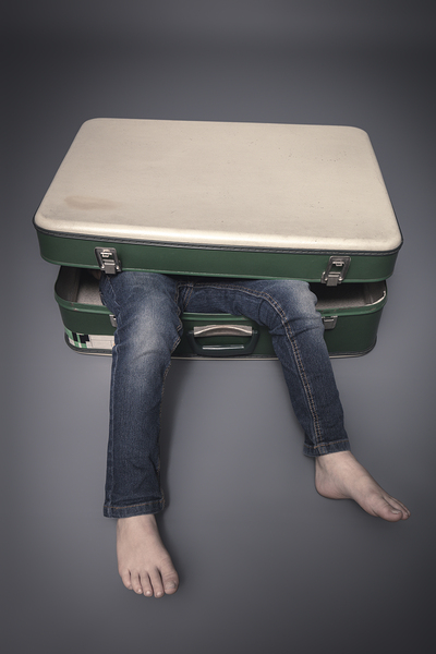 legs protruding from an old suitcase 