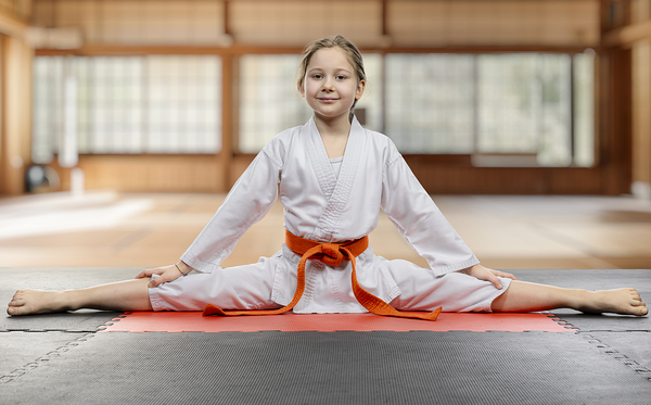 Young girl practicing karate split in dojo Print