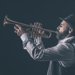 profile view of a jazz trumpet player with beard and hat.