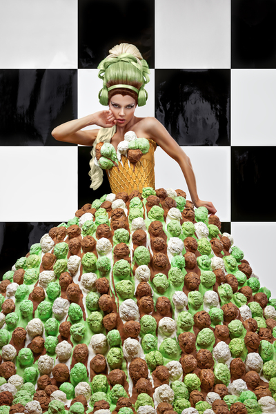 Beautiful young woman wearing a high three-color hairstyle and an ice cream scoops dress with an ice cream cone corset posing in front of a checkerboard wall by Artmood Visualz