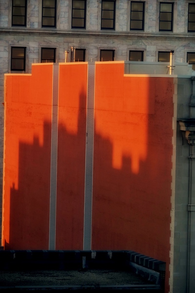 City Shadows at Dawn On Orange Wall by Rik Katz
