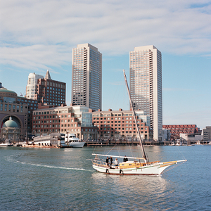 Sailboat floating by harbour with city skyline