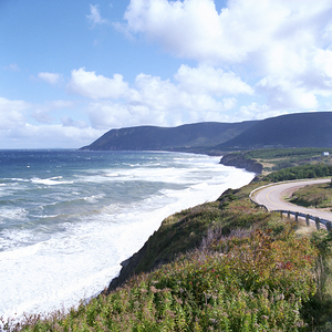 Road along shore with waves and mountains behind