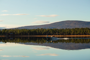 Man on boat calm lake autumn colors