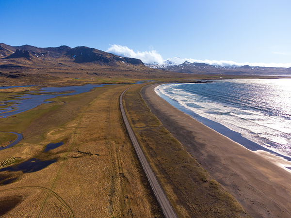 Iceland scenic route Snaefellsnes pensinsula volcano in the background covered in snow empty road with the ocean and waves. Print