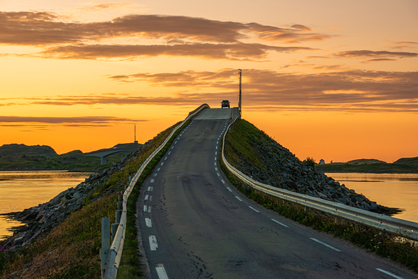 A car on the Fredvang bridges in Lofoten Norway with a beautiful sunset over the sea.  Print