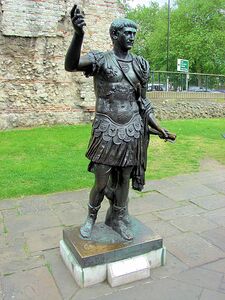 Statue of the Emperor Trajan near a section of  Roman Wall London