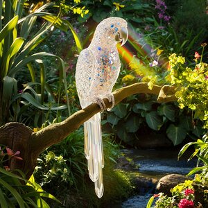 A beautiful Parrot made of transparent colorful crystals sitting in a garden