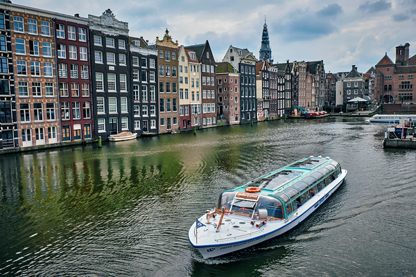 Canal cruise tourist boat in Amsterdam at Damrak canal and pier by Dmitry Rukhlenko