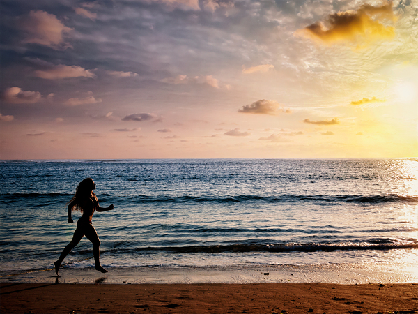 Beautiful athletic woman running along sea beach in the morning by Dmitry Rukhlenko