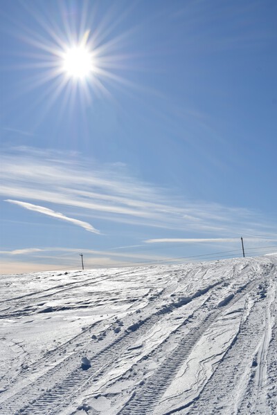 A snowmobile trail under a blue sky by Laprise