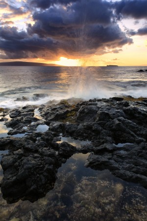Water splashing onto the lava rock along the coast at sunset; Hawaii, United States of America